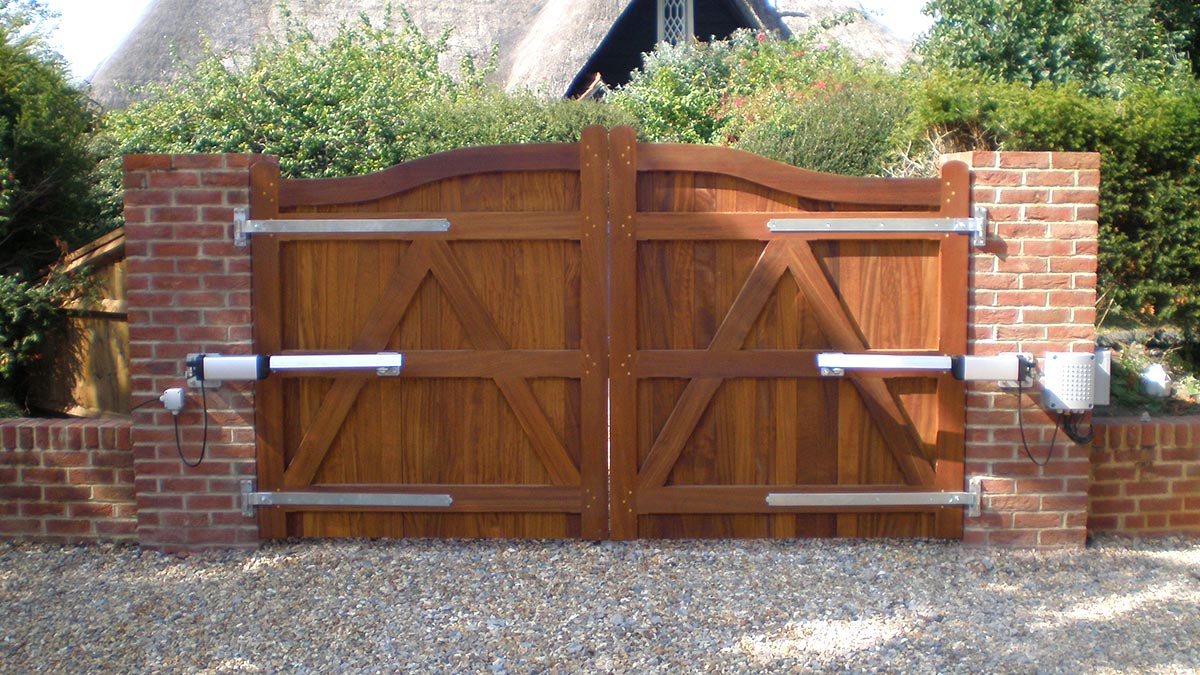 Automatic driveway gates in stained hardwood with swan-neck profile at Ampfield, Romsey