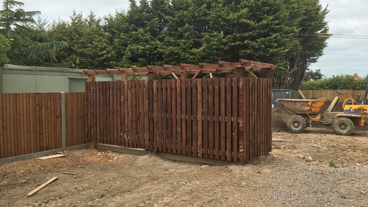 Wooden palisade to conceal bin store at new build housing in Toddington